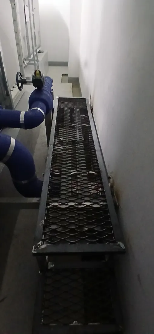배관이 지나는 좁은 통로 옆에 길게 설치된 메탈라스 발판